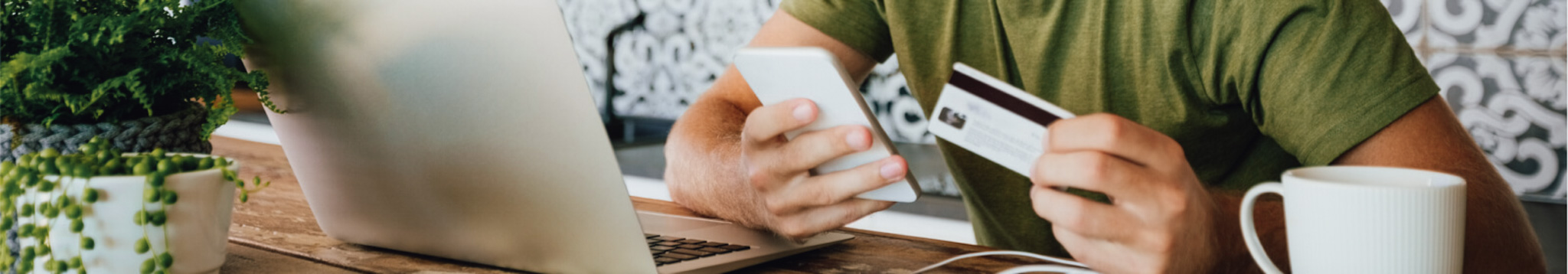 a person holding a debit/credit card preparing to make an online purchase