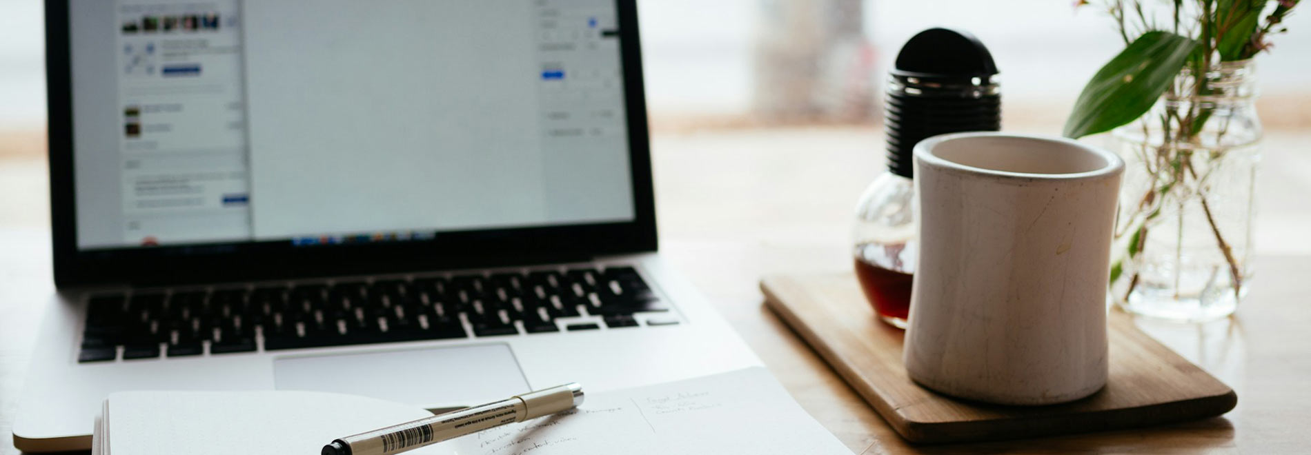 A laptop computer on a desk with coffee